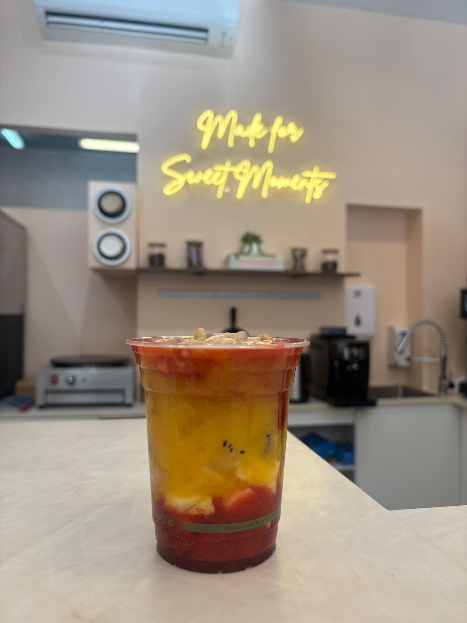 A fresh fruit cup on the counter under the 'Made for Sweet Moments' neon sign