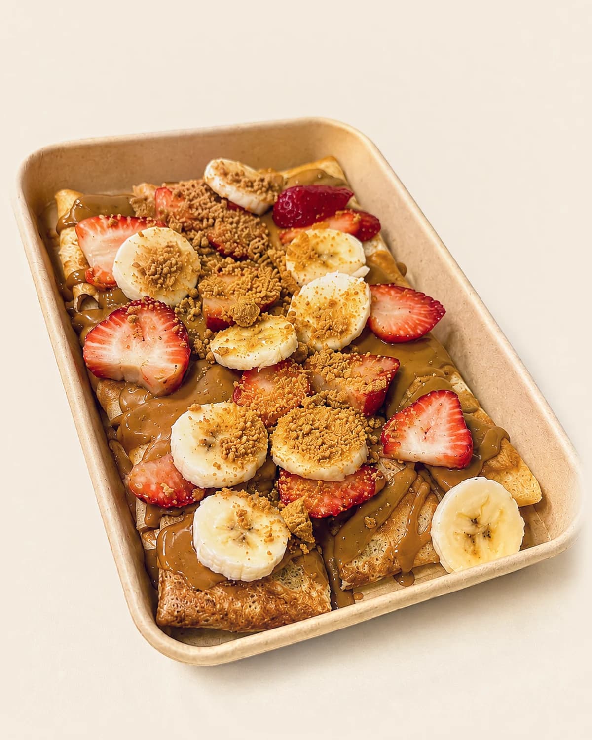 A Nabil's crêpe tray topped with strawberries, banana and crushed Biscoff