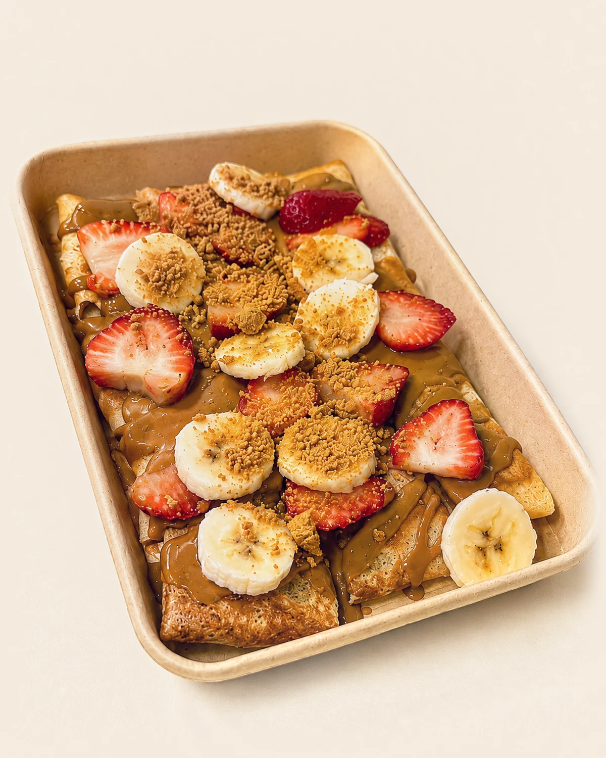 A Nabil's crêpe tray topped with strawberries, banana and crushed Biscoff